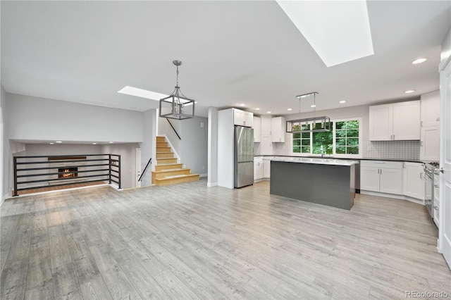 6451 S Hoyt St, Littleton, CO 80123 - kitchen with a skylight, open floor plan, appliances with stainless steel finishes, decorative backsplash, and white cabinetry
