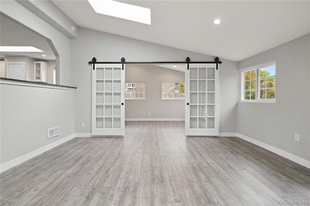 6451 S Hoyt St, Littleton, CO 80123 - unfurnished living room with a barn door, lofted ceiling, wood finished floors, a skylight, and recessed lighting