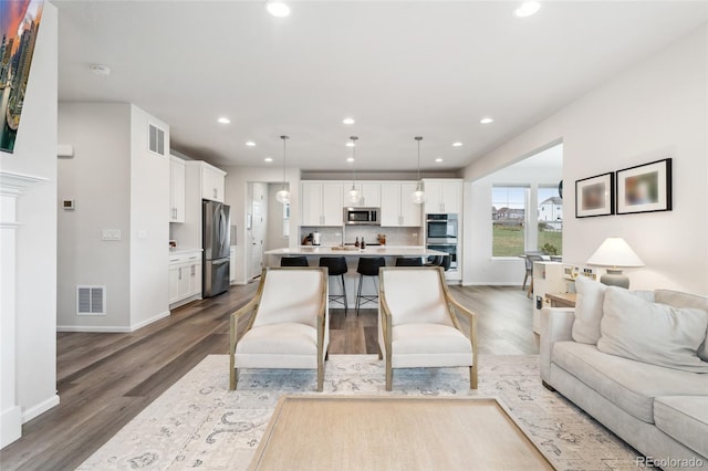 living room with visible vents, recessed lighting, baseboards, and wood finished floors