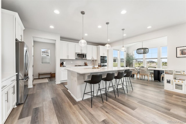 kitchen with white cabinets, appliances with stainless steel finishes, light countertops, recessed lighting, and backsplash