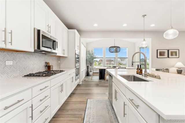 kitchen featuring tasteful backsplash, wood finished floors, a sink, light countertops, and stainless steel appliances