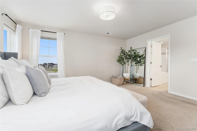 carpeted bedroom with baseboards, visible vents, and ensuite bathroom
