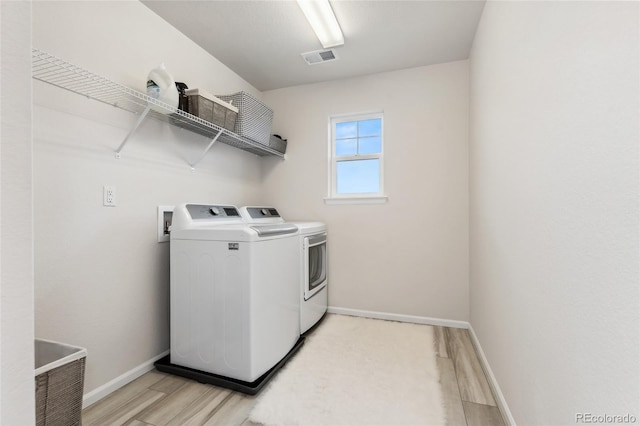 laundry room with light wood-style floors, baseboards, laundry area, and independent washer and dryer
