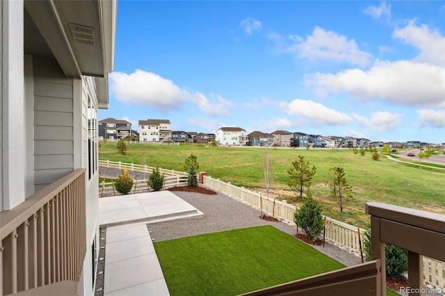 view of yard featuring a patio, fence, and a residential view
