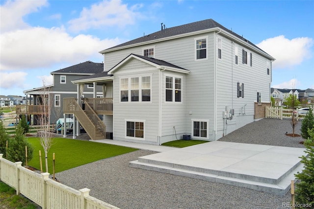 rear view of house with a gate, a patio area, a fenced backyard, a yard, and stairs