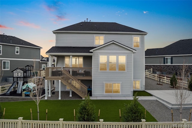 back of property at dusk with stairs, a playground, a lawn, a patio, and fence private yard