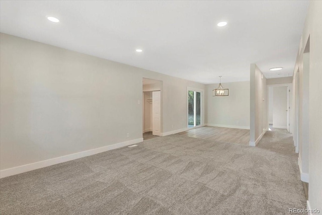 spare room with recessed lighting, light colored carpet, and baseboards