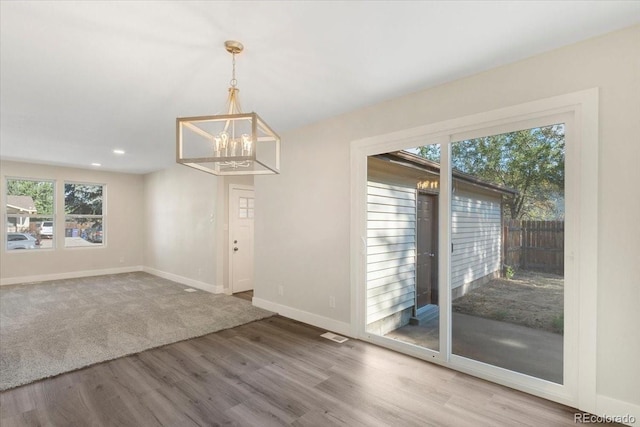 unfurnished dining area with wood finished floors, baseboards, visible vents, an inviting chandelier, and recessed lighting