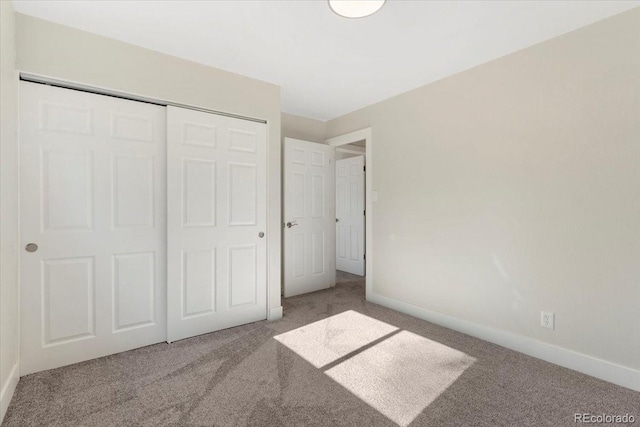 unfurnished bedroom with carpet flooring, baseboards, and a closet