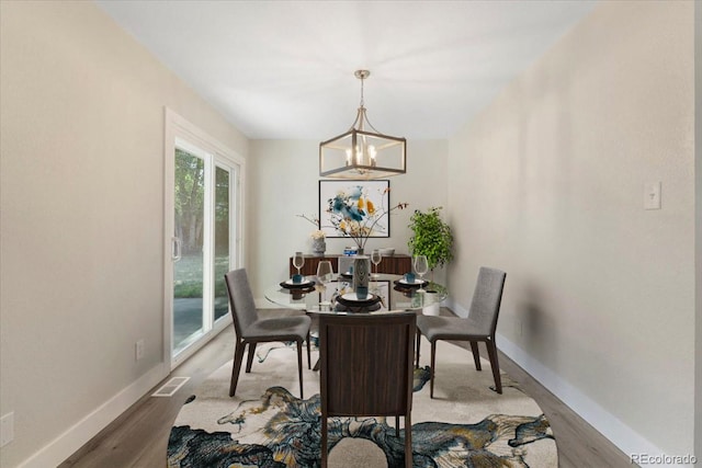 dining room featuring a notable chandelier, wood finished floors, visible vents, and baseboards