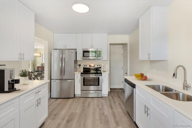 kitchen featuring appliances with stainless steel finishes, light wood-type flooring, white cabinetry, and sink