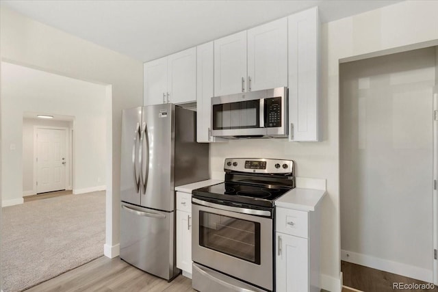 kitchen with light wood finished floors, baseboards, light countertops, appliances with stainless steel finishes, and white cabinets