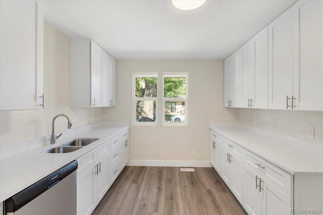 kitchen with a sink, white cabinetry, light wood-style floors, light countertops, and dishwasher