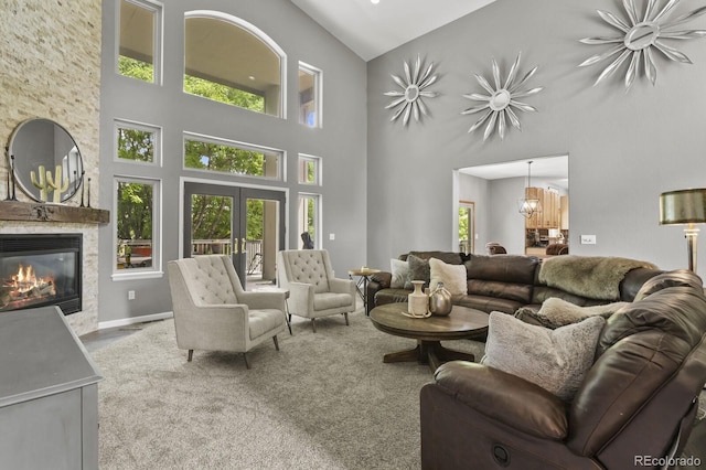 living room featuring a high ceiling, a stone fireplace, and plenty of natural light