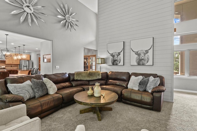 living room featuring carpet flooring, high vaulted ceiling, and a notable chandelier