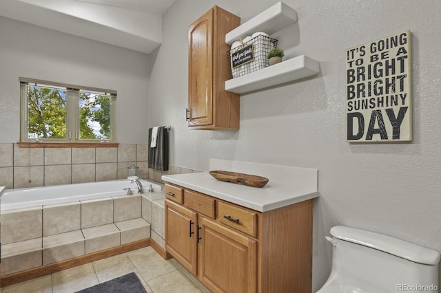 bathroom featuring toilet, vanity, a relaxing tiled tub, and tile patterned floors