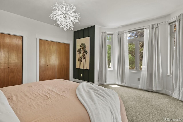 bedroom with an inviting chandelier, multiple closets, and carpet