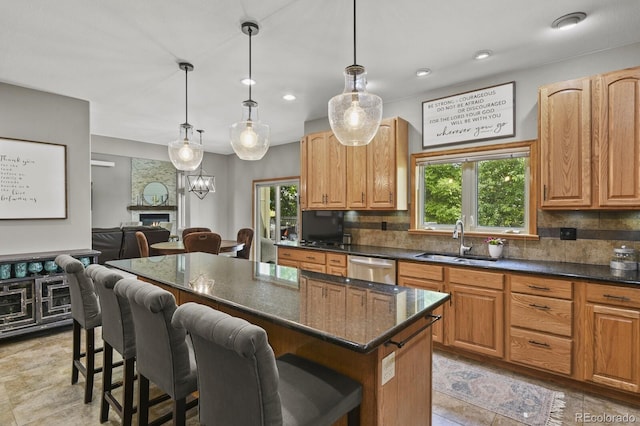 kitchen with a kitchen island, backsplash, hanging light fixtures, sink, and a breakfast bar area