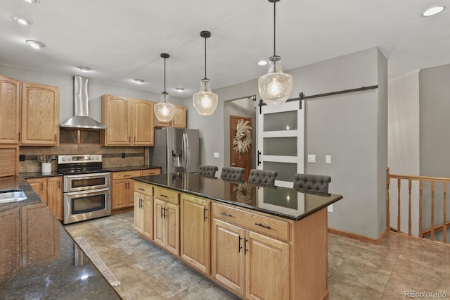 kitchen with stainless steel appliances, wall chimney exhaust hood, decorative light fixtures, a center island, and a barn door