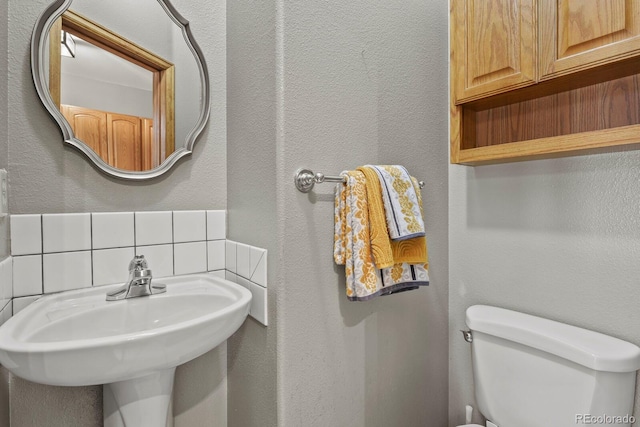 bathroom featuring toilet, sink, and tasteful backsplash