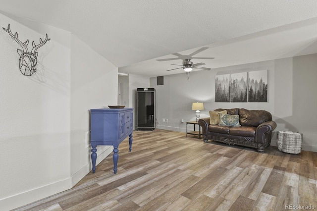 living room featuring a textured ceiling, hardwood / wood-style flooring, and ceiling fan