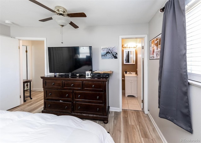 bedroom featuring a sink, ceiling fan, light wood finished floors, and ensuite bath