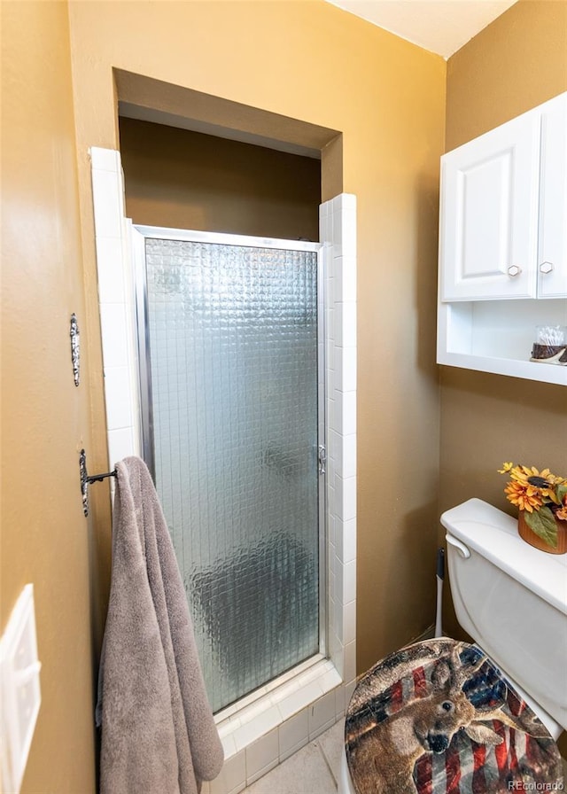 bathroom featuring toilet, a stall shower, and tile patterned flooring