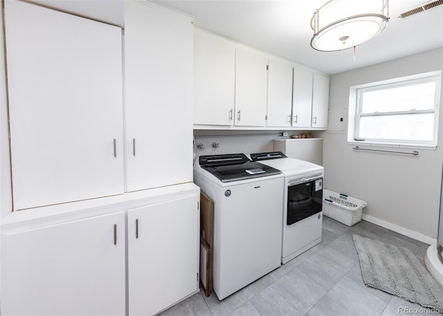 clothes washing area featuring separate washer and dryer, visible vents, baseboards, and cabinet space