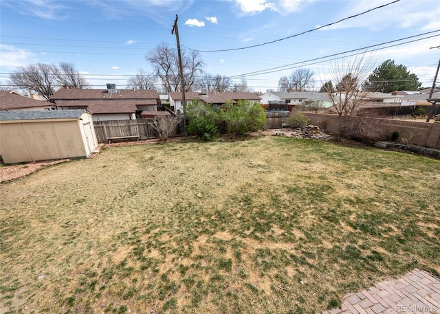 view of yard featuring an outbuilding, a fenced backyard, and a storage unit