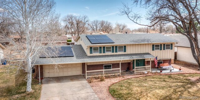 traditional-style home featuring roof with shingles, driveway, covered porch, and brick siding