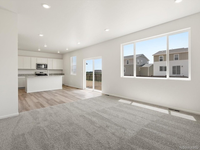 4694 Sugarcane St, Johnstown, CO 80534 - unfurnished living room with light carpet, recessed lighting, and light wood-style flooring