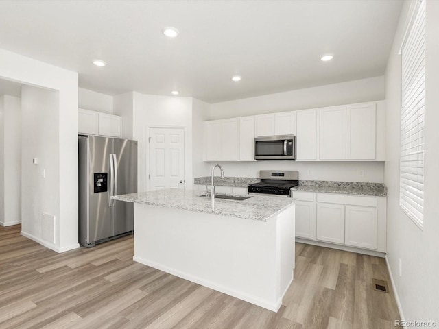 4694 Sugarcane St, Johnstown, CO 80534 - kitchen featuring stainless steel appliances, light wood-style flooring, white cabinets, a kitchen island with sink, and recessed lighting