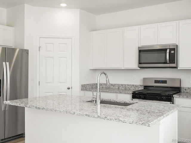 4694 Sugarcane St, Johnstown, CO 80534 - kitchen with stainless steel appliances, white cabinets, a kitchen island with sink, light stone counters, and recessed lighting