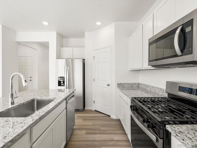 4694 Sugarcane St, Johnstown, CO 80534 - kitchen featuring stainless steel appliances, light wood-style flooring, white cabinets, light stone counters, and recessed lighting