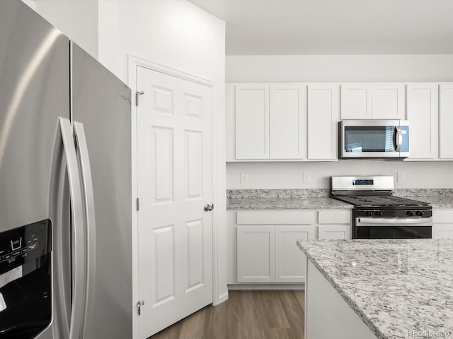 4694 Sugarcane St, Johnstown, CO 80534 - kitchen with stainless steel appliances, white cabinets, dark wood-style floors, and light stone countertops