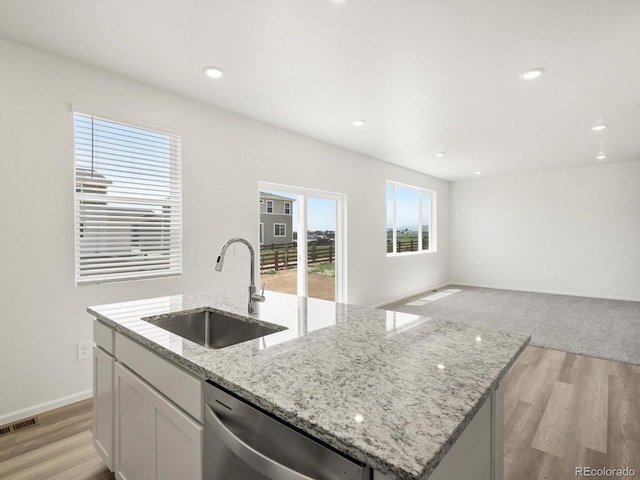4694 Sugarcane St, Johnstown, CO 80534 - kitchen with dishwasher, a center island with sink, light wood-style floors, white cabinetry, and recessed lighting