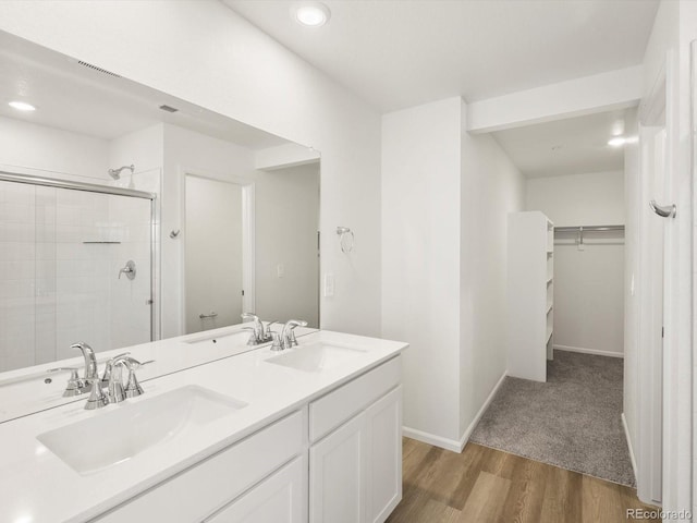 4694 Sugarcane St, Johnstown, CO 80534 - bathroom featuring a stall shower, a walk in closet, double vanity, wood finished floors, and recessed lighting
