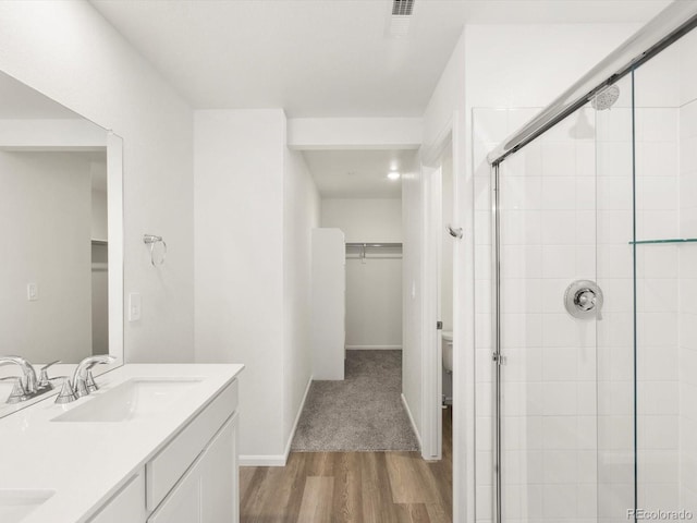 4694 Sugarcane St, Johnstown, CO 80534 - bathroom featuring a spacious closet, a stall shower, wood finished floors, and double vanity