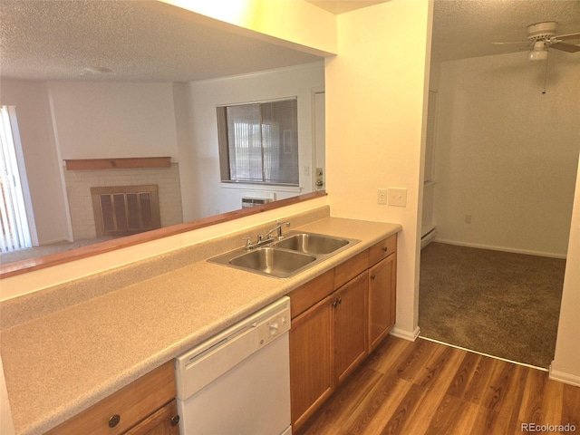 kitchen with ceiling fan, white dishwasher, sink, a brick fireplace, and dark hardwood / wood-style floors