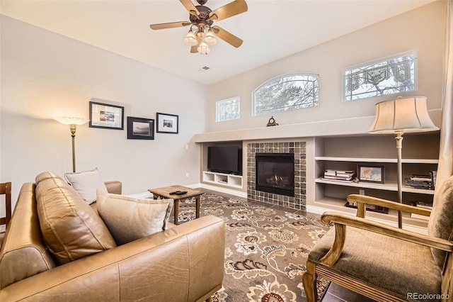 living area with a tiled fireplace and a ceiling fan