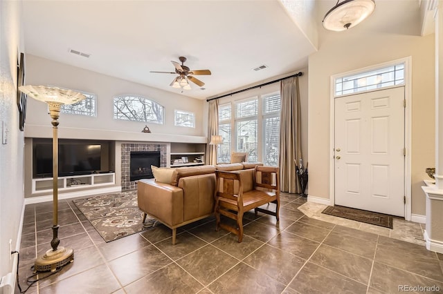 entryway with baseboards, a brick fireplace, visible vents, and a ceiling fan