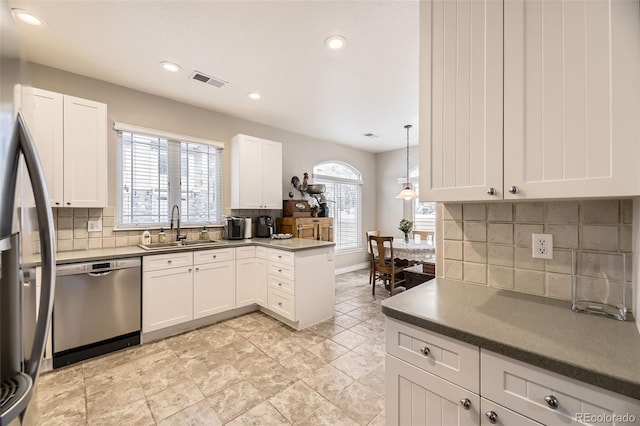 kitchen with appliances with stainless steel finishes, dark countertops, white cabinets, and a sink