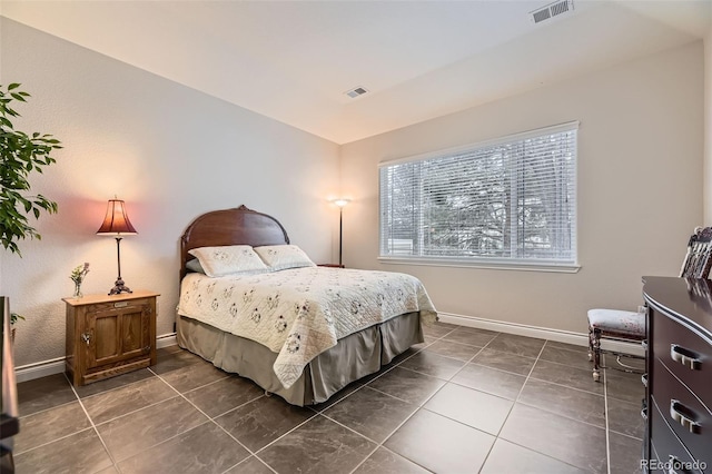 bedroom with dark tile patterned floors, visible vents, and baseboards