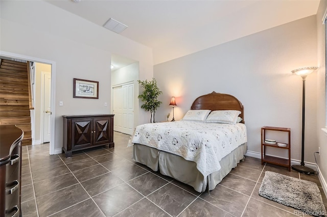 bedroom with dark tile patterned flooring, visible vents, and baseboards