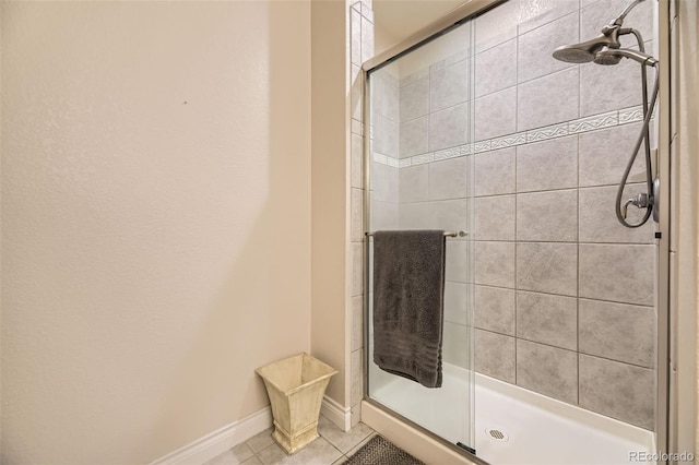 full bath featuring baseboards, tiled shower, and tile patterned floors