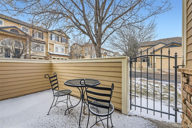 snow covered patio featuring fence and a residential view