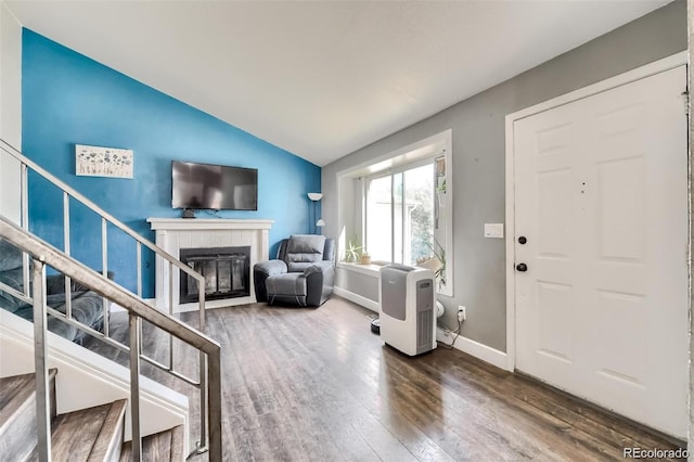 foyer entrance with hardwood / wood-style flooring, vaulted ceiling, and a tile fireplace