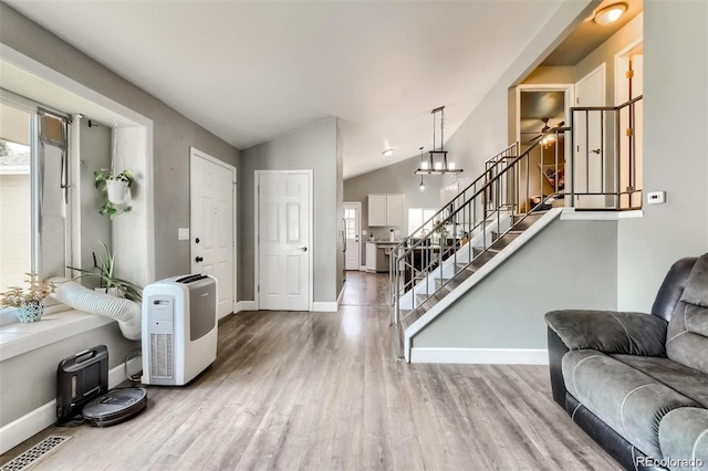 entryway with wood-type flooring and vaulted ceiling