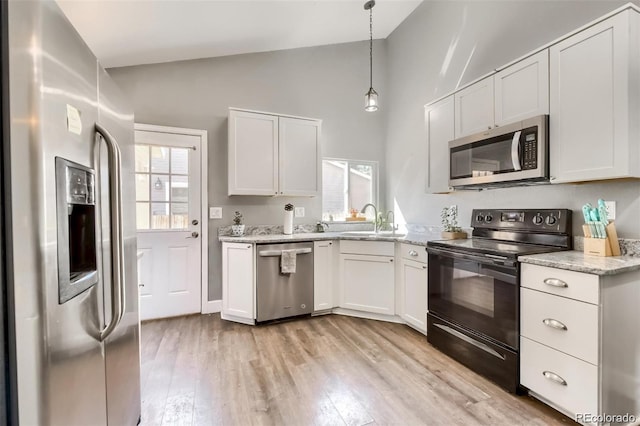 kitchen featuring white cabinetry, hanging light fixtures, stainless steel appliances, and lofted ceiling