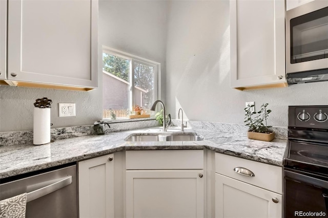 kitchen featuring sink, light stone countertops, white cabinets, and appliances with stainless steel finishes